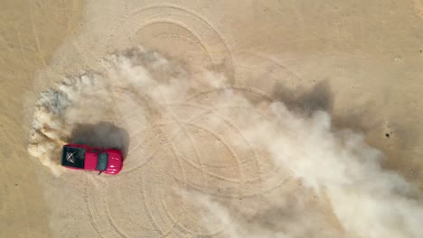 red truck making doughnuts in the desert sand, aerial top down view