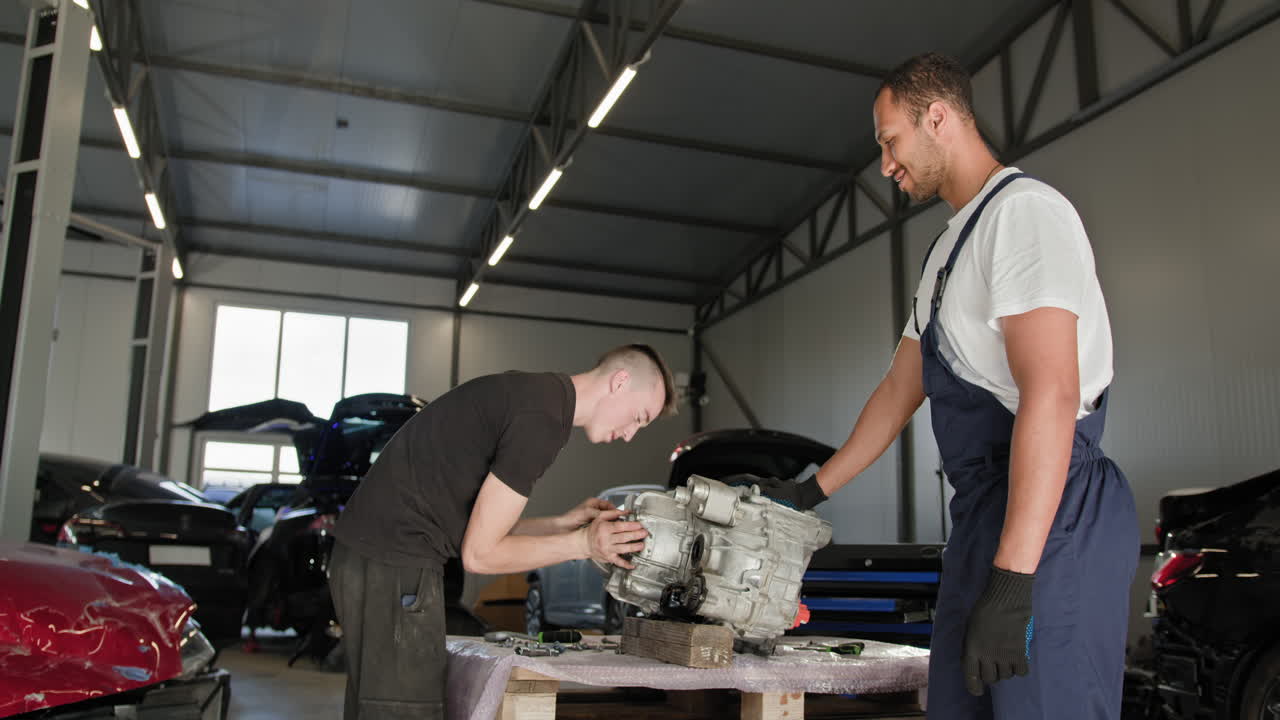 mecánicos de automóviles trabajando en una transmisión en un garaje