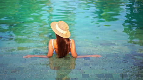 Espalda-De-Mujer-Con-Sombrero-De-Verano-En-La-Piscina-Relajándose-En-Un-Día-Soleado,-Fotograma-Completo