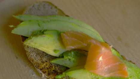 top view of female putting salmon on avocado toast