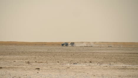 a mirage in the wake of a 4x4 tourist vehicle crossing makadikgadi salt pan in botswana on a sweltering hot day