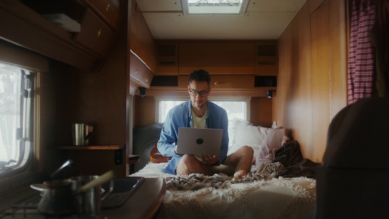 Uomo che lavora al portatile in un camper