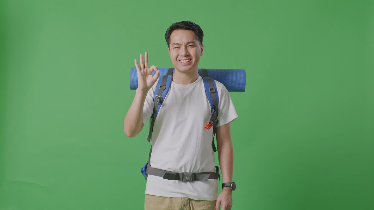 hombre con mochila dando la señal de ok en la pantalla verde