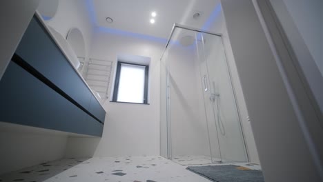 a sleek and modern bathroom featuring a frameless glass shower, terrazzo flooring, and ambient blue led lighting, creating a tranquil and contemporary space