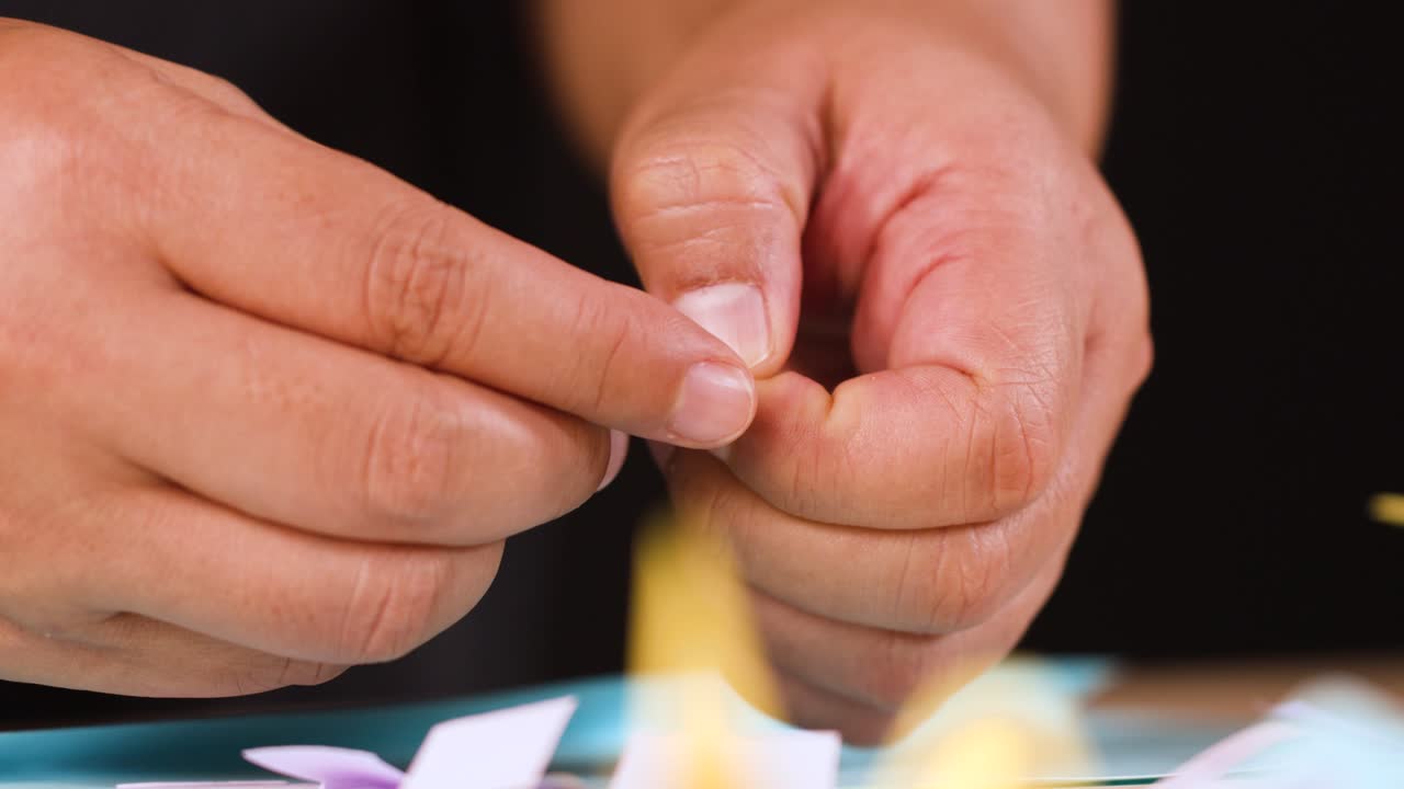 Primo piano di mani che piegano con cura carta azzurra per un progetto di origami