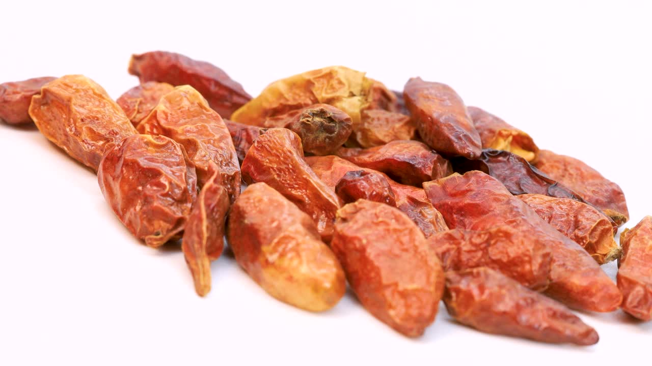 흰색 표면에서 회전하는 오렌지 드라이 칠리의 기울어진 샷, 보기 닫기
