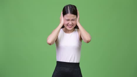 young beautiful asian businesswoman covering ears from loud noise