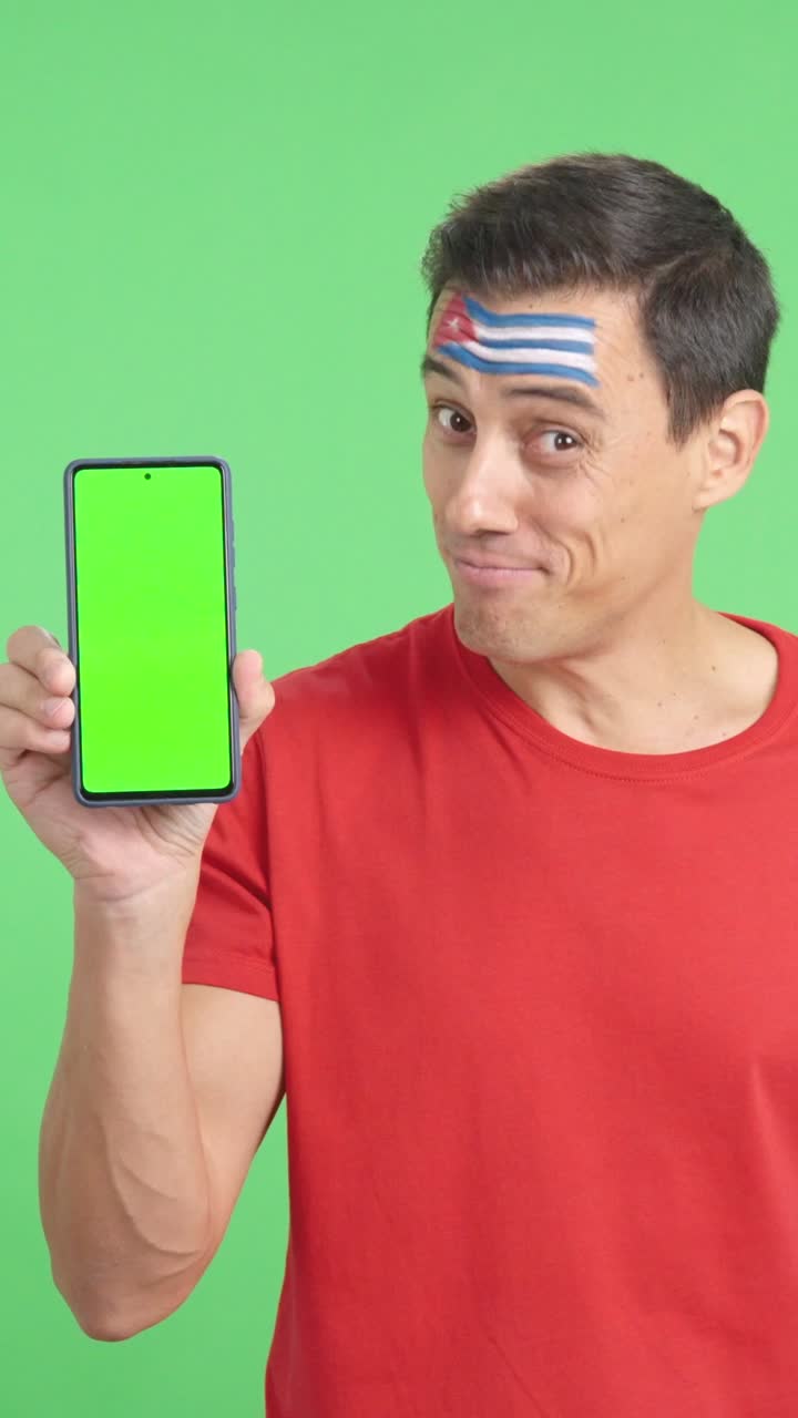 Cuban supporter looking at his mobile smiling and showing it