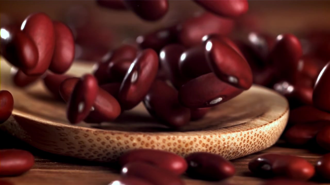 Red Kidney Beans Falling onto a Wooden Spoon in Slow Motion