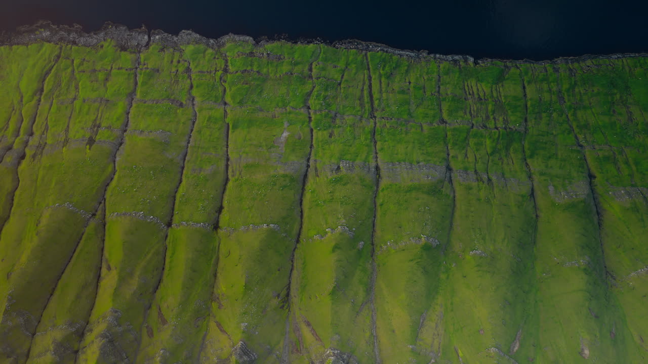 Aerial View of Green Grassy Cliffs and Dark Water