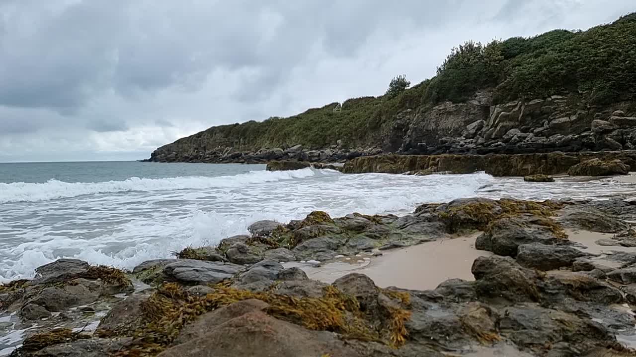 천천히 움직이는 바다의 파도가 바위가 있는 해안선을 가로질러 흐르고, 바다의 절벽이 하늘을 가로지르고 있습니다.
