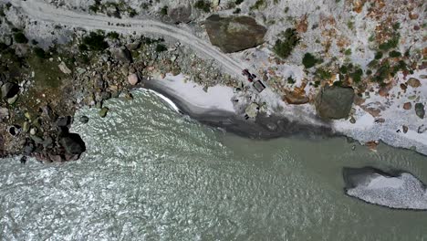 Aerial-shot-of-workers-collecting-construction-sand-on-the-bank-river-of-Hunza