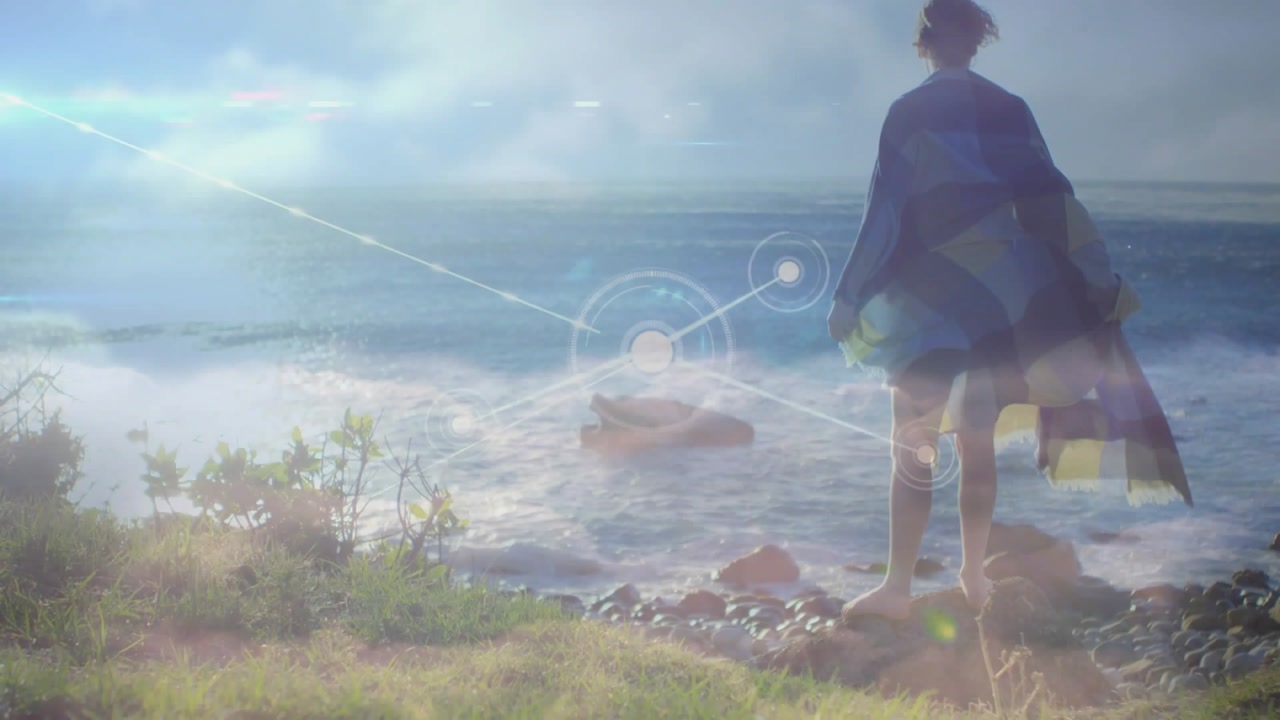 Woman standing on rock facing horizon, HUD emerging offshore overlaying woman visualizing tech