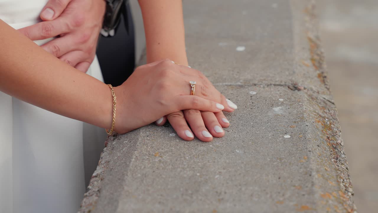 Detailed close-up shot of a newlywed couple's tender embrace, showcasing their hands and rings in natural light, conveying love and intimacy on their special day