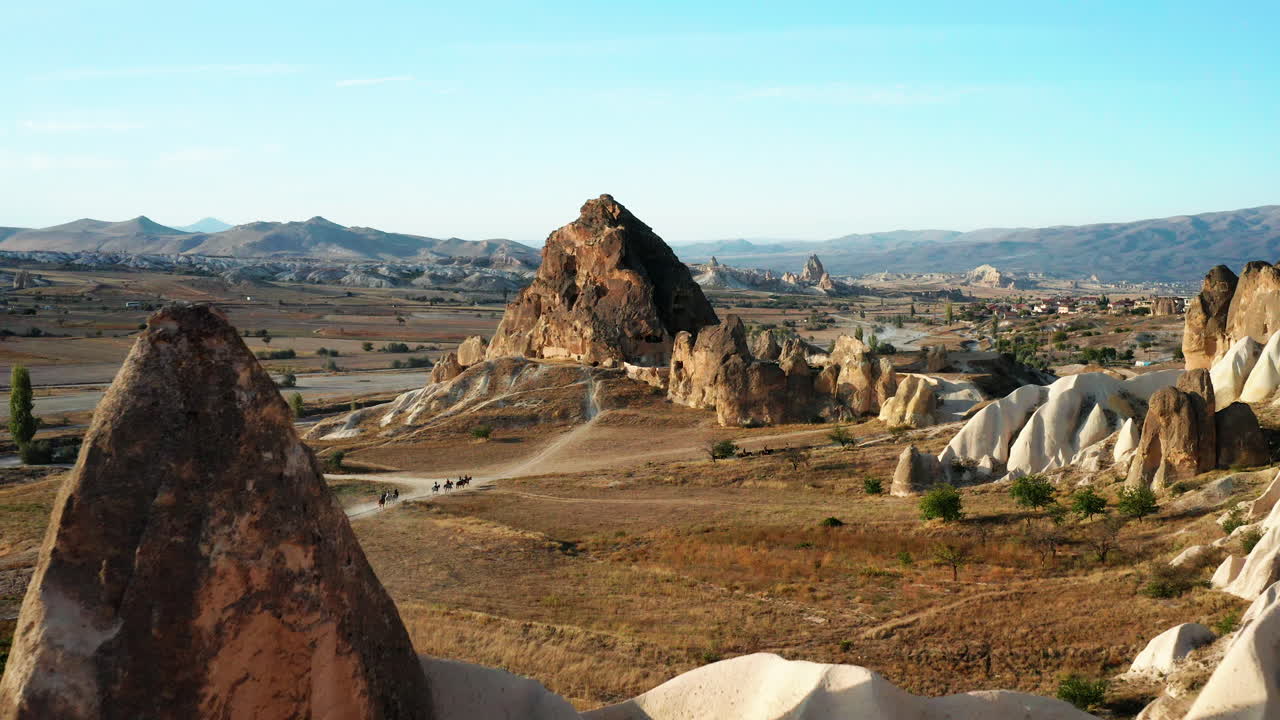 enorme roca con piedra tallada en la región de capadocia de turquía con gente a caballo hasta la puesta del sol