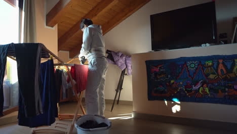 woman hangs clothes on drying rack inside her own house