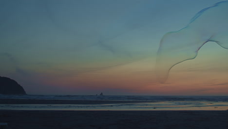 giant bubble floats across vivid sunset beachscape, blue hour