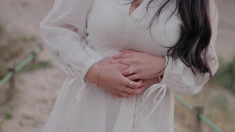 Close-up-of-a-couple-embracing,-focusing-on-the-woman's-hands-with-rings-and-a-bracelet,-and-the-man's-hands-on-her-waist