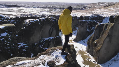 joven viajero caminando por un camino empinado en el cañón fjadrargljufur en invierno