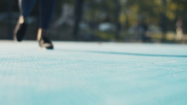 Close Up Of Female Feet In Black Trainers Jogging On Sport Court On Sunny Day And Then Hands Fixing Laces
