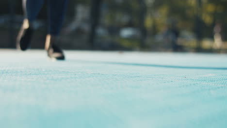 close up of female feet in black trainers jogging on sport court on sunny day and then hands fixing laces