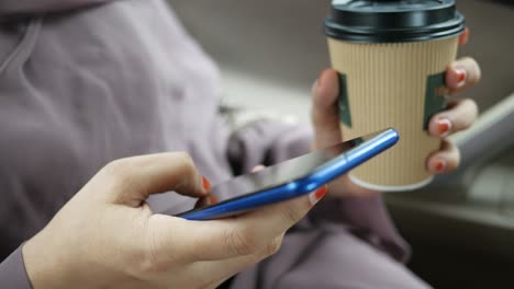 mujer usando teléfono inteligente mientras bebe café