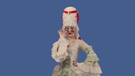 portrait of courtier lady in white vintage lace dress, wig and sunglasses smiles coquettishly and flirts. young woman posing in studio with blue screen background. close up. slow motion ready 59.94fps