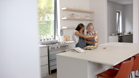 baking together, asian grandmother and granddaughter decorating cupcakes in modern kitchen