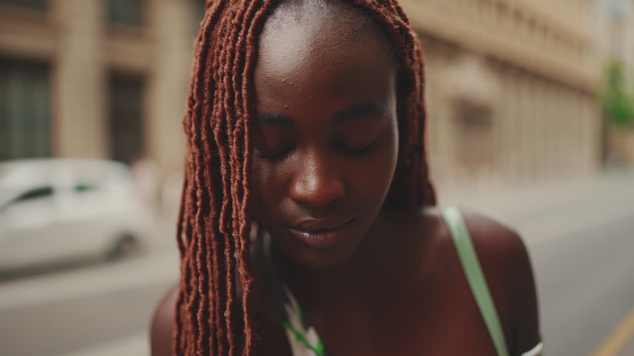 Ritratto di una giovane donna afroamericana con trecce castane per strada