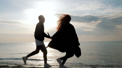 young couple running on the sandy beach. pair having fun, fooling, holding hands, enjoying moment. romantic sunset during spring travel vacation holiday honeymoon. playful girl and man in love
