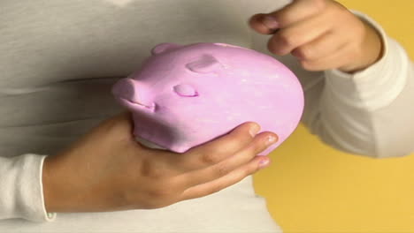 a woman places coins into a piggy bank