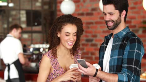 Smiling-hipster-friends-discussing-over-a-smartphone