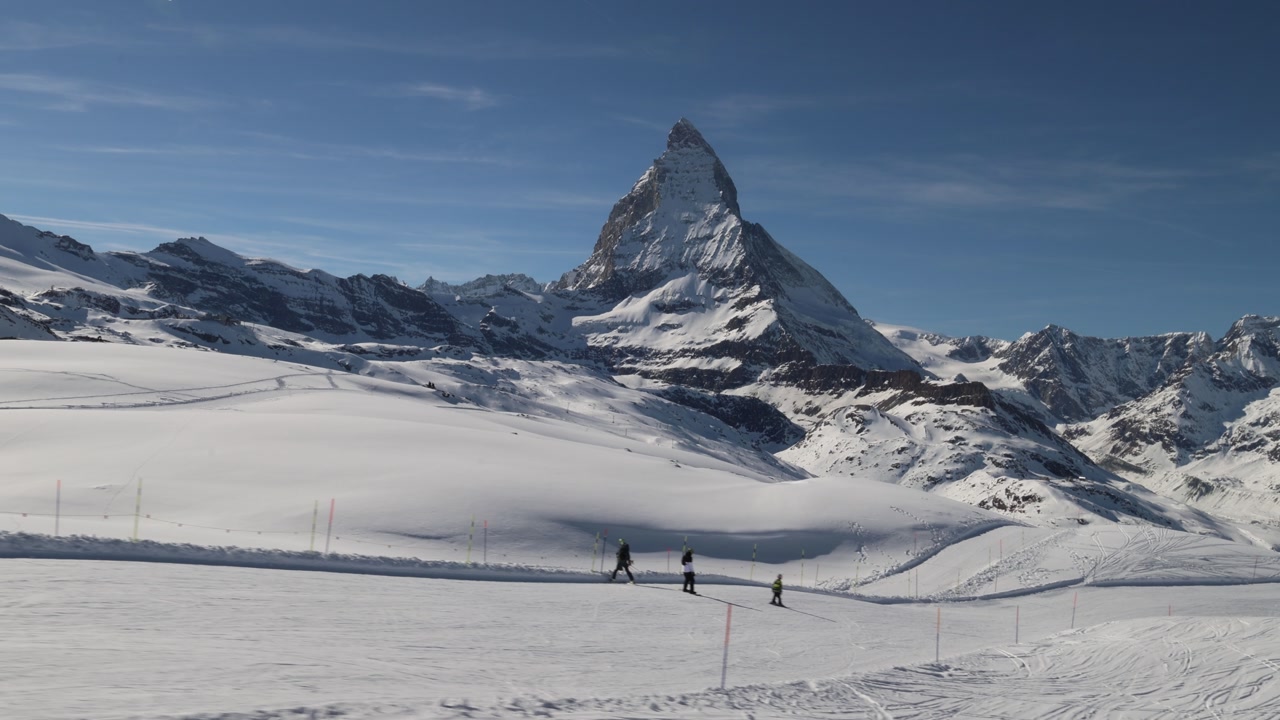People skiing in Zermatt ski resort below Matterhorn, establishing wide view.