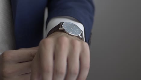 close up man in a suit puts a watch