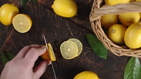 male hand with a knife cut the lemon into pieces.