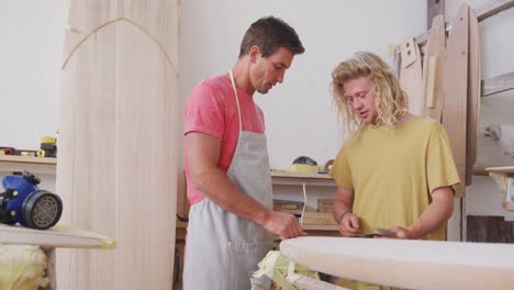 dos fabricantes de tablas de surf caucásicos discutiendo el proyecto con tablas de surf en el fondo