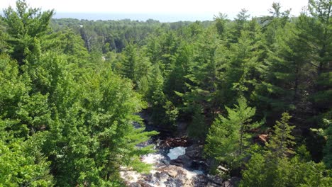 Luftdrohnenaufnahme,-Die-Dem-Schnell-Fließenden-Weißen-Wasser-Der-Duchesnay-Wasserfälle-Folgt,-Während-Der-Fluss-über-Die-Felsen-Und-Durch-Einen-Wald-In-Der-Nordbucht-Von-Kanada-Stürzt