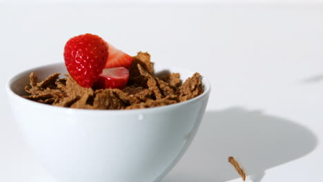strawberries falling in a wheat cereals bowl