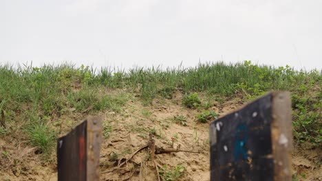 Sand-hill-with-grass-at-Olesko-shooting-range,-wooden-target-wall-in-foreground