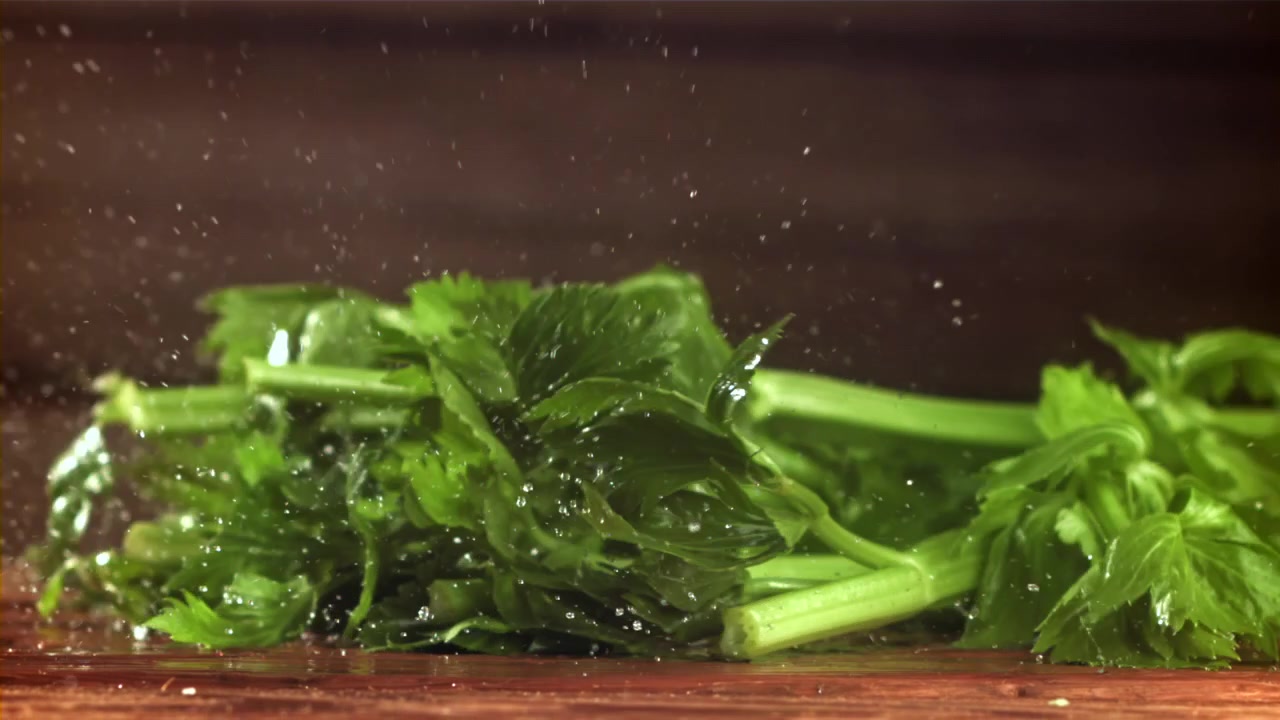Fresh Celery Falling onto Wet Wooden Surface in Slow Motion