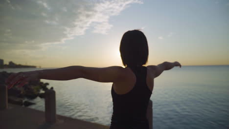 woman with glasses doing yoga by the water at sunrise. slow motion.