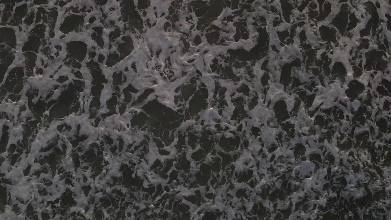 un intenso primer plano de las olas rodando y burbujeando en la orilla