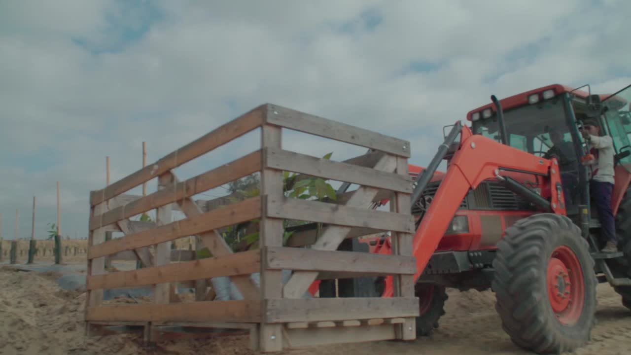 Tractor driver pulls up with crate in forklift and exits vehicle, SLOW MOTION