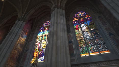 vibrant stained glass windows and murals inside vienna's votive church, sunlight streaming through