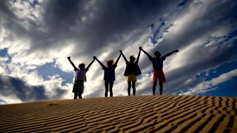 children holding hands on sand dunes