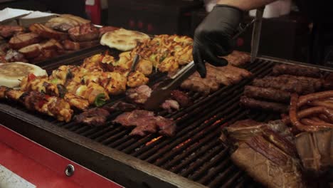 natural organic sheep meat cooking on a wood and charcoal grill barbeque outside at a traditional meat festival, close-up shot of chef cutting up the meat directly on the grill with a chef's knife