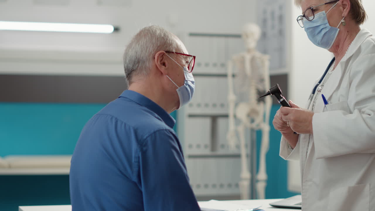 Senior physician doing ear examination with otoscope