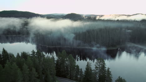 Aerial-shot,-a-lake-with-fog-and-you-pass-a-road-to-it