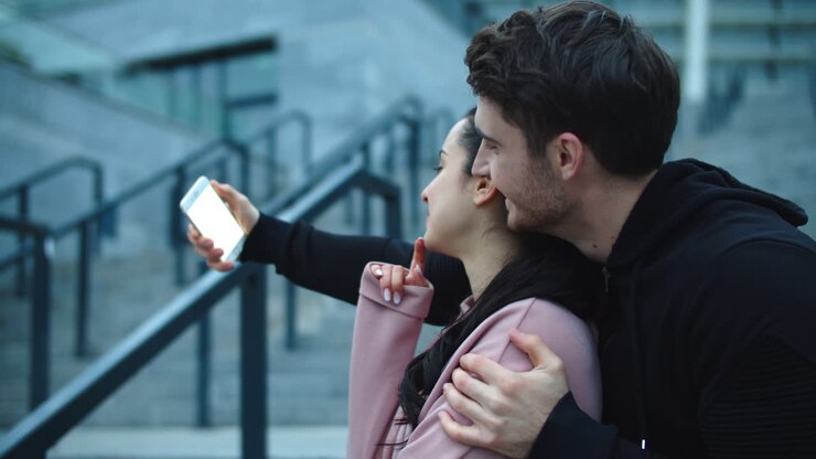 Coppia che si abbraccia in posa per un selfie.