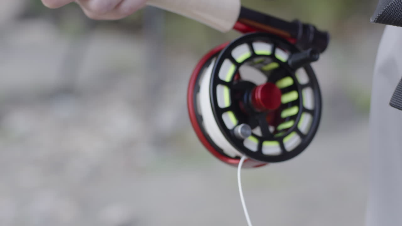 슬로우 모션으로 릴에서 플라이 라인을 꺼내는 플라이 어부